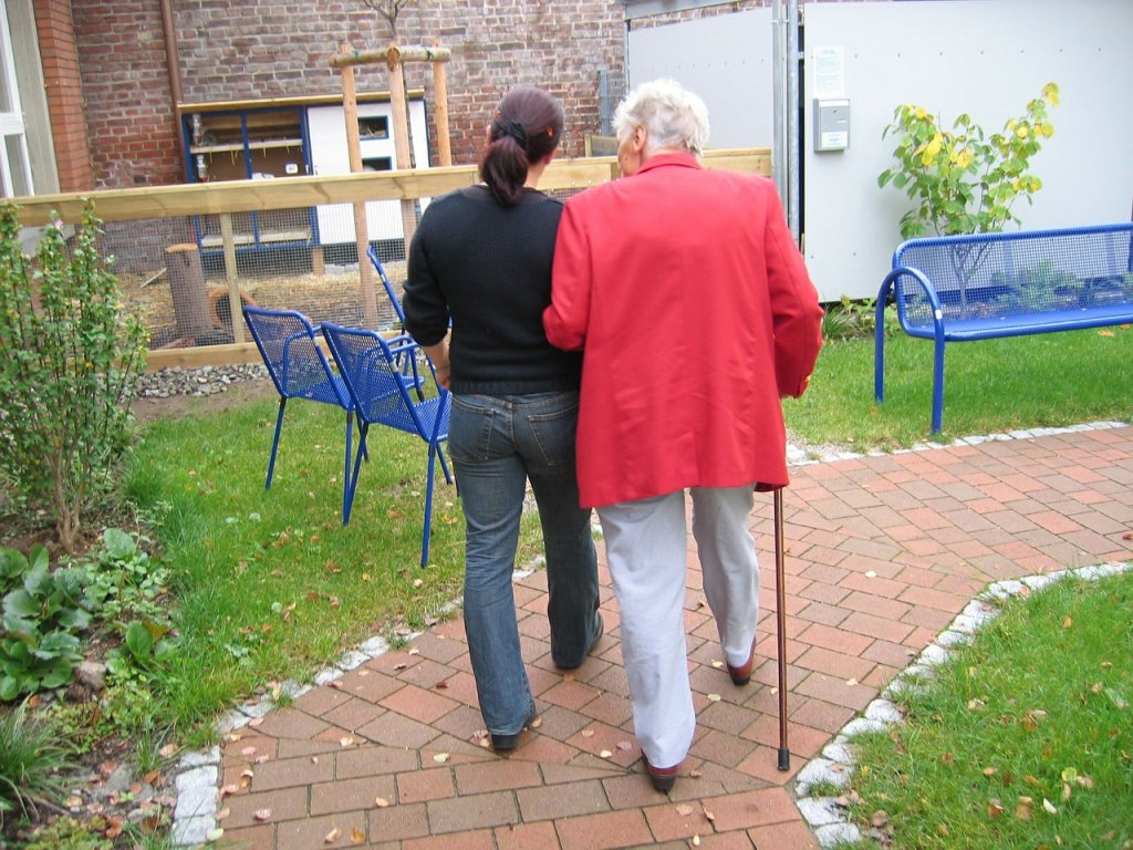 Image of older person being assisted to walk along pathway